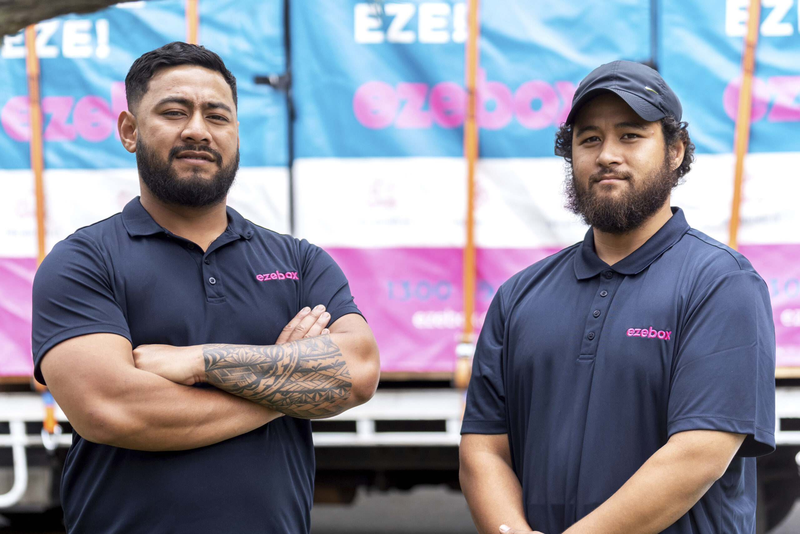 Two friendly Ezebox team members standing confidently in front of a truck